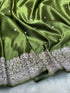 Green fabric with white floral embroidery on a light gray background