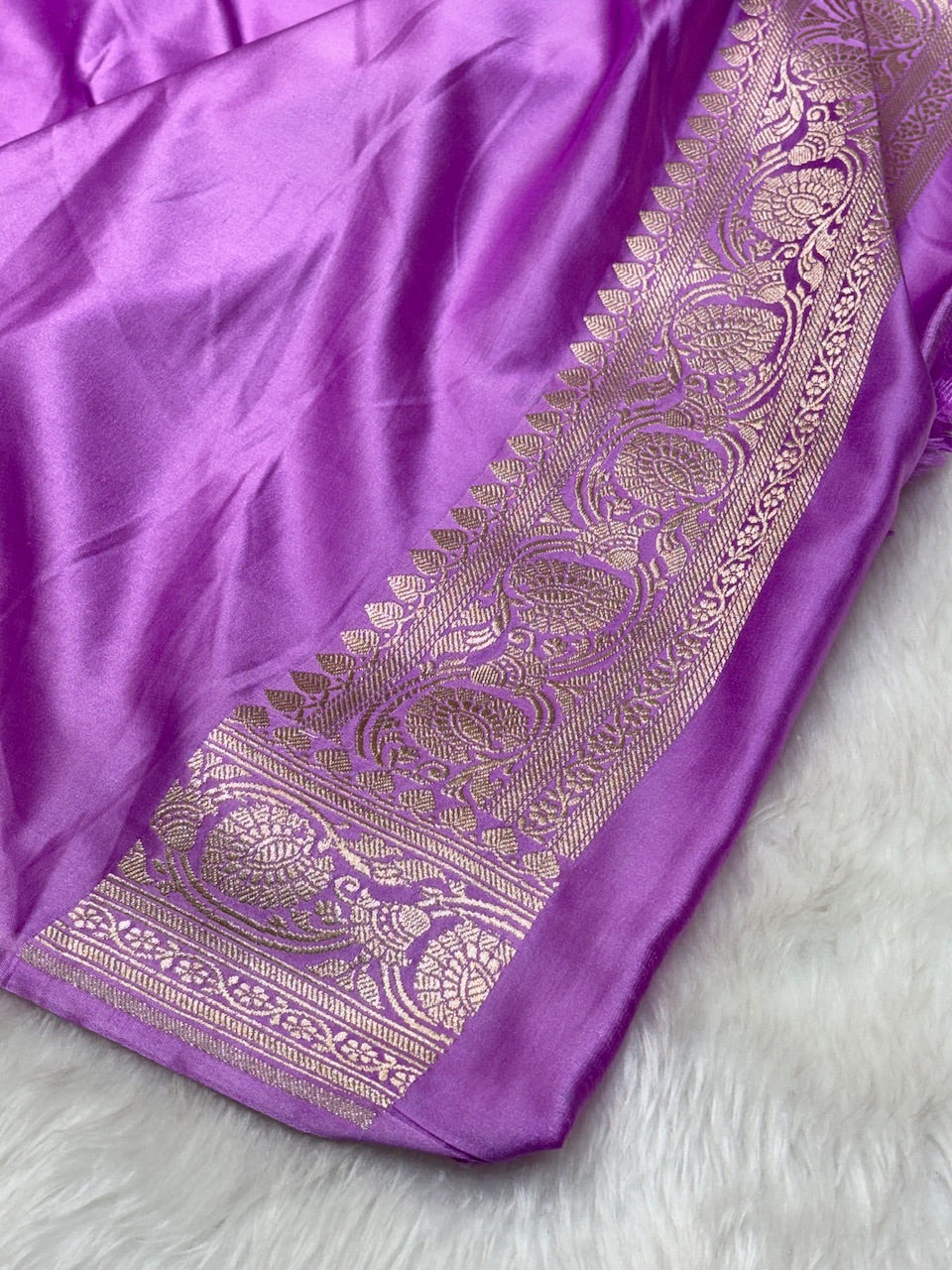 Purple fabric with intricate gold embroidery on a white background