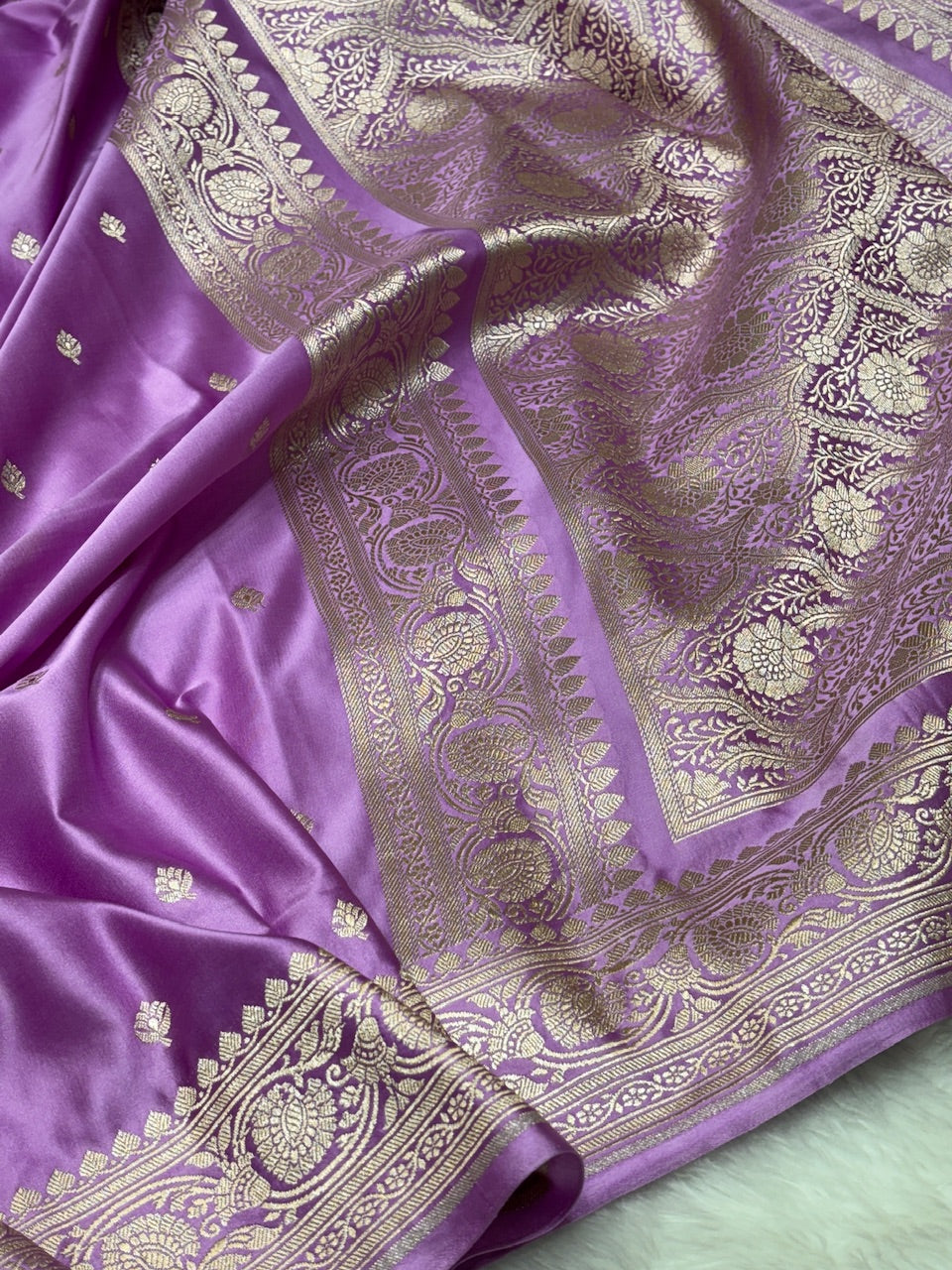 Purple saree with gold and silver intricate patterns on a green background