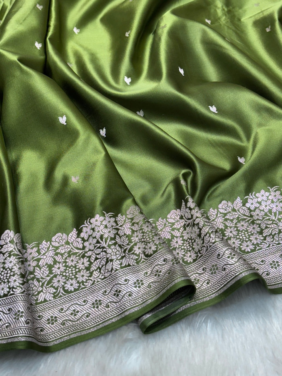 Green fabric with white floral embroidery on a light gray background